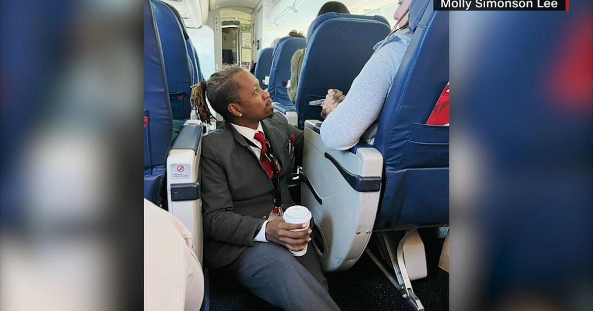  Flight attendant sits on floor to comfort nervous passenger 